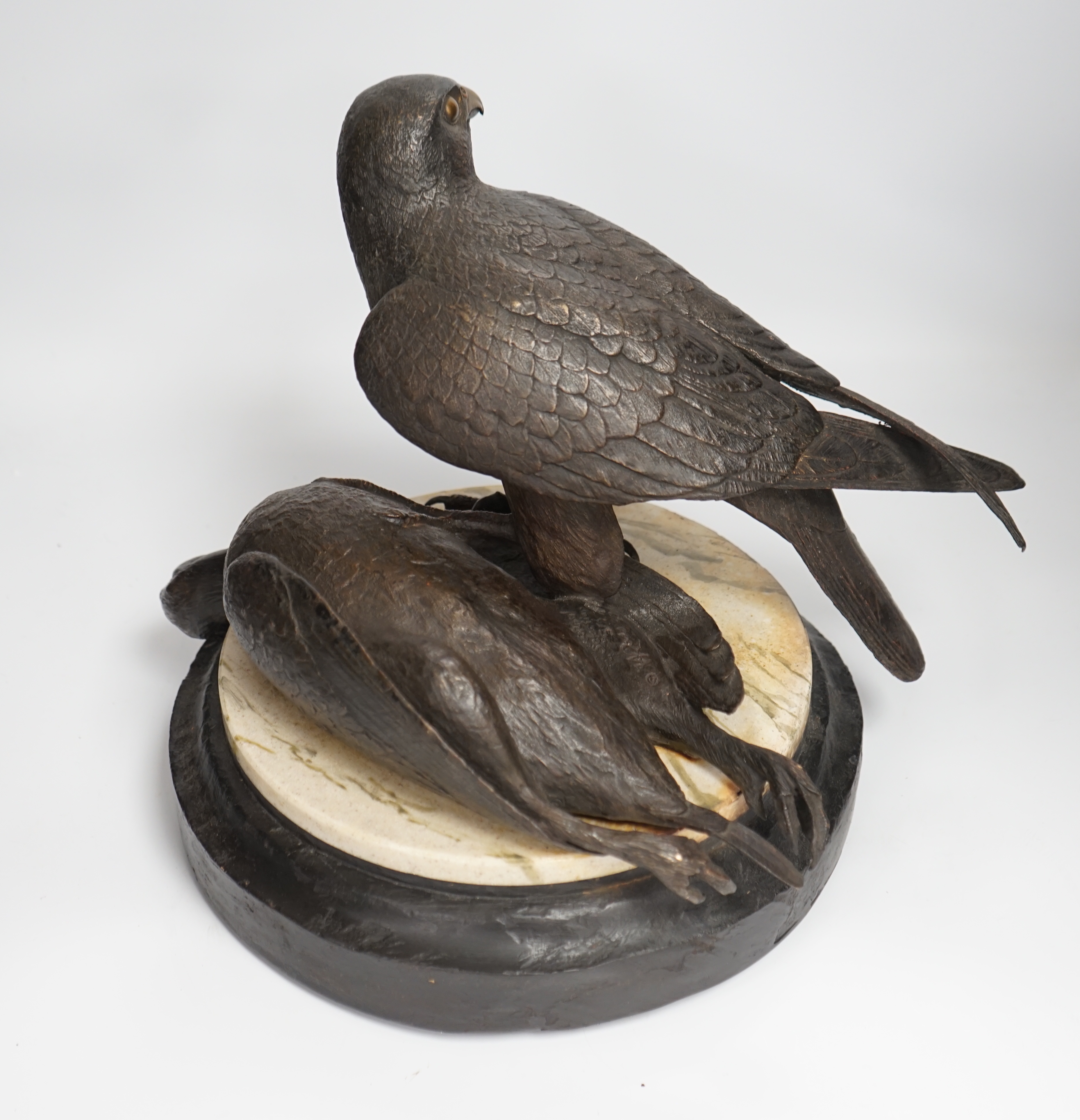 A limited edition bronze bird of prey with a kill, on a faux marble disc and painted wooden stand, 29cm high